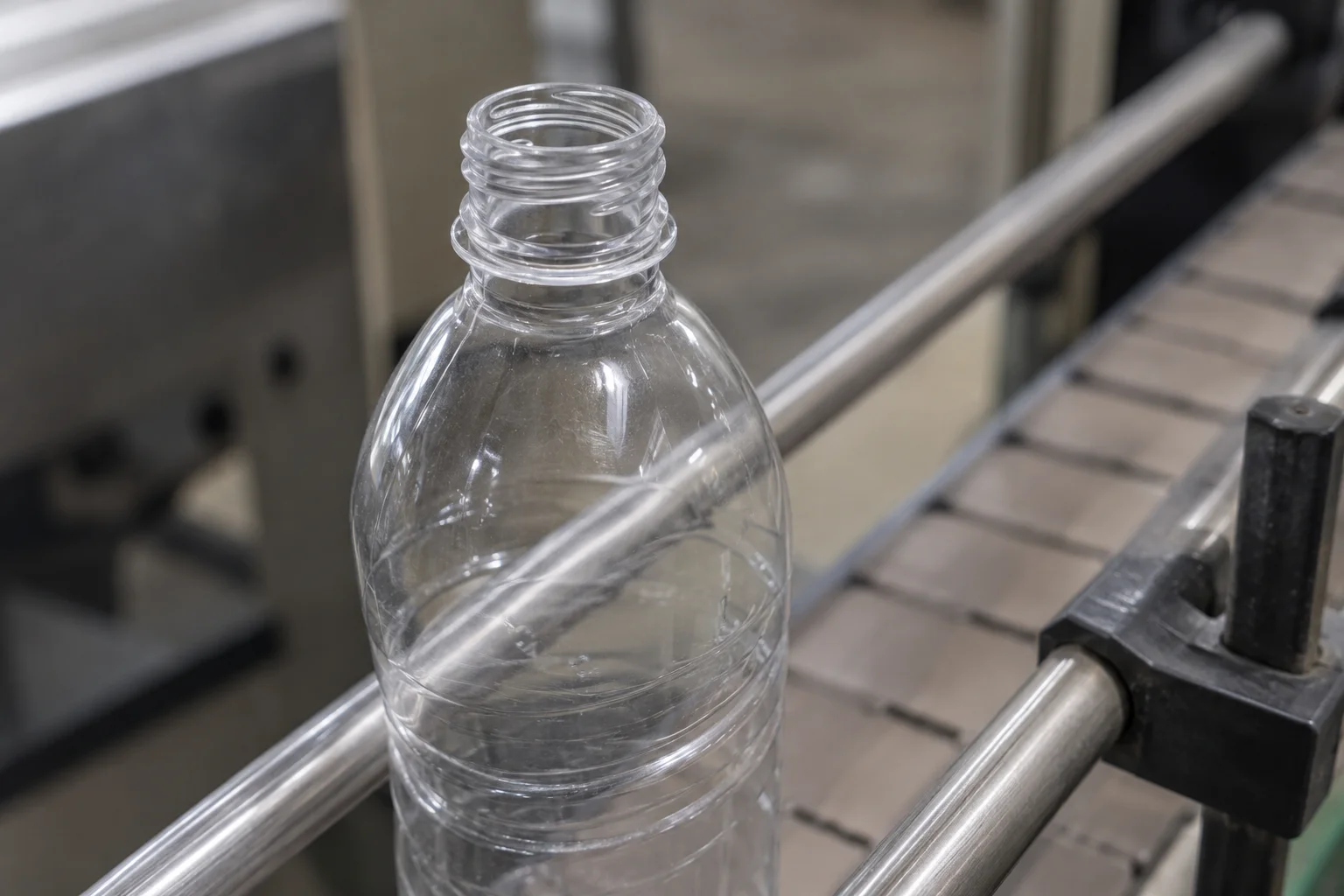Transparent bottle between metal guide rails on a conveyor